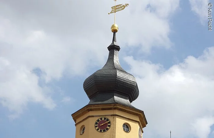 Gelbe Kirchenfarbe mit grauer Kirchturmspitze.