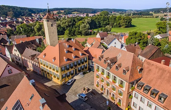 Luftbild der Altstadt Windsbach. Eine breit gepflasterte Straße an der Häuser im fränkischen Baustil stehen. Ein großer Stadtturm ragt über die Dächer hinweg.
