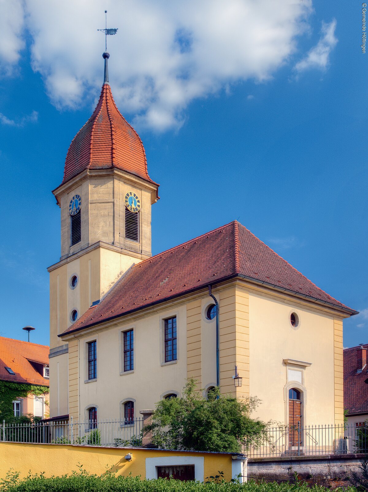 Gelbe Kirche unter strahlendem blauen Himmel.