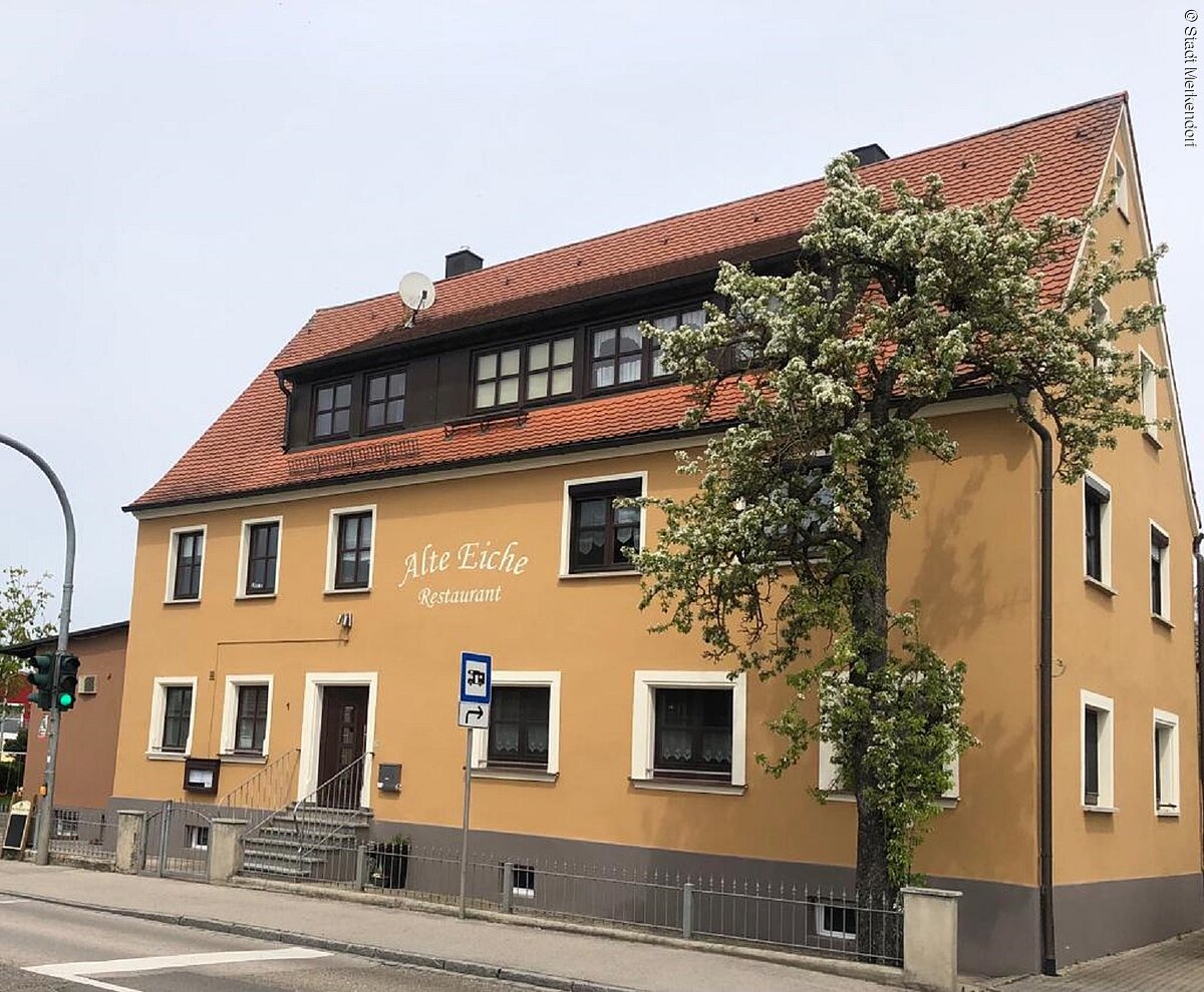Außenansicht des Restaurants Alte Eiche in Merkendorf. Ein Beige-braunes Haus mit rotem Dach, direkt an der Bundesstraße gelegen.