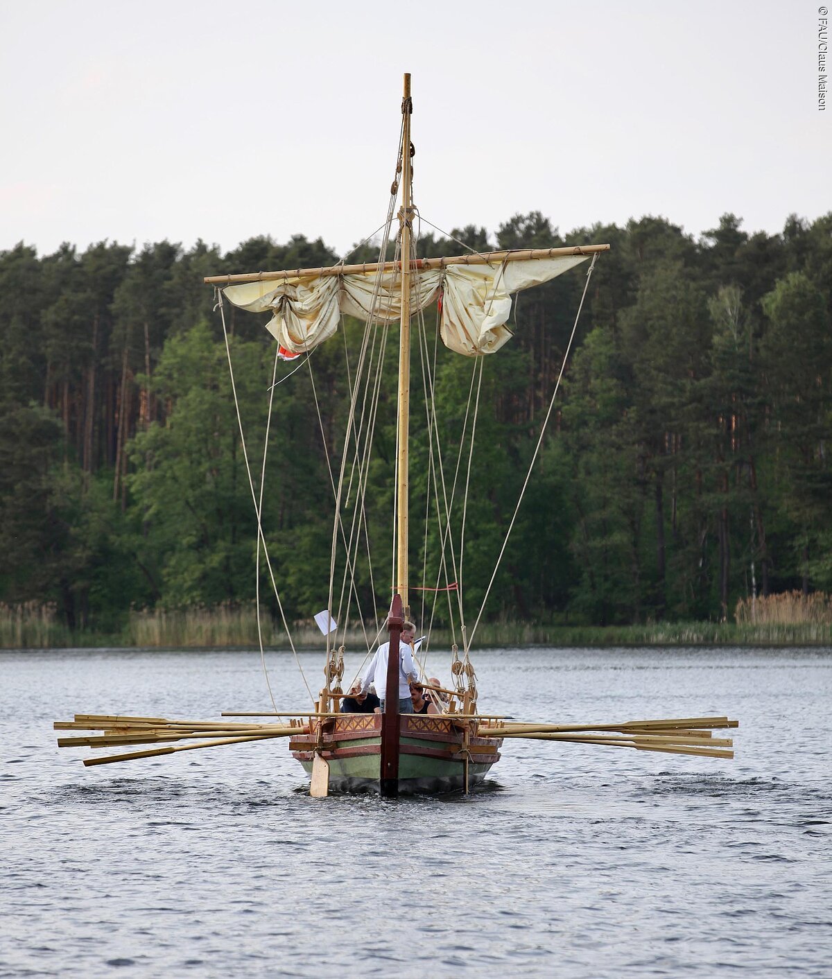 das Römerboot fridericiana alexandrina navis, kurz FAN, auf dem Dechsendorfer Weiher. Im Hintergund erstreckt sich ein Wald entlang des Ufers.