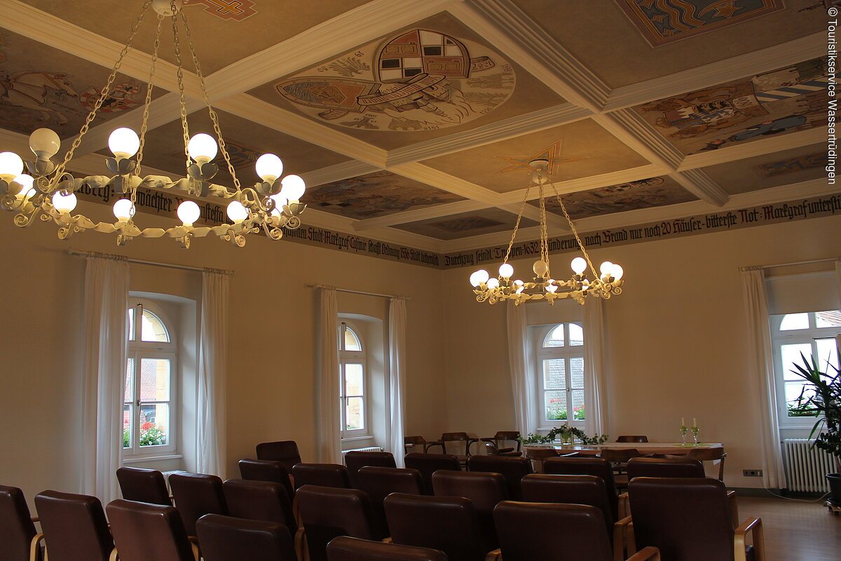Zwei große runde Lampen hängen im Rathaussaal.