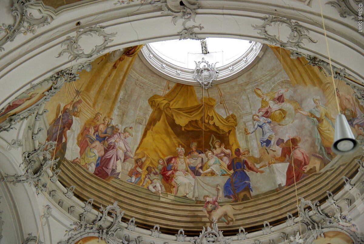 Innenansicht der Kuppel der St. Nikolauskirche. Malereien auf weißem Grund. Ansammlung von Menschen in langen edlen Gewändern.