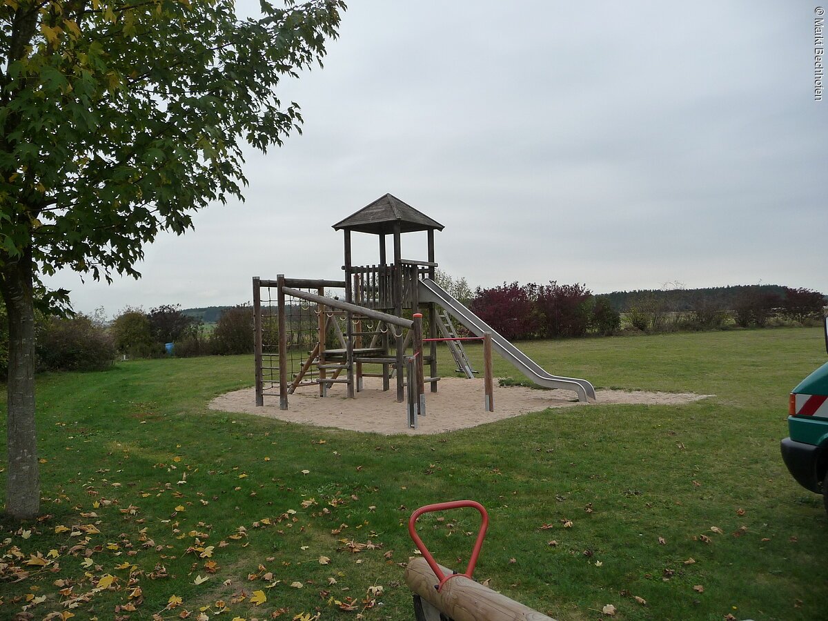 Spielturm mit Rutsche und Wippe vorhanden.