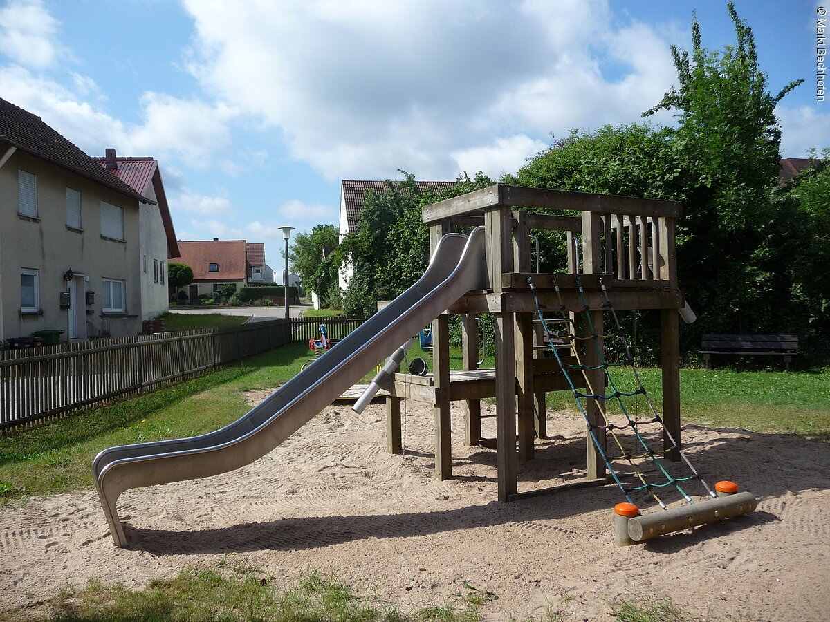 Silberne Rutsche mit Holklettergerüst.
