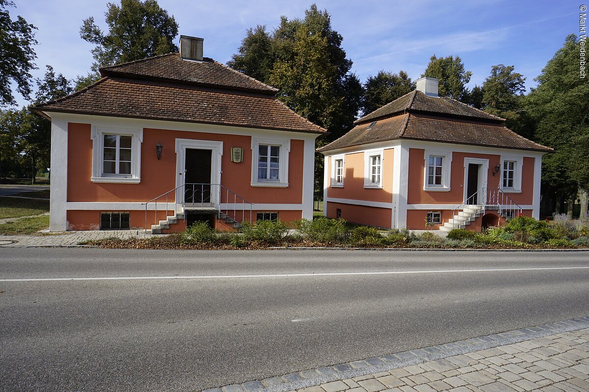 Zwei fast identische barocke Häuschen nebeneinander. Beide mit roter Fassade. Beide mit Mansardendächern.