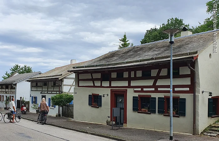 Ein Jurahaus hat am Tag des offenen Denkmals geöffnet. Eine Schar Besucher steht vor dem Haus. Das Haus ist mit Legschieferdach, Holzbalken und grünen Fensterläden ausgestattet.