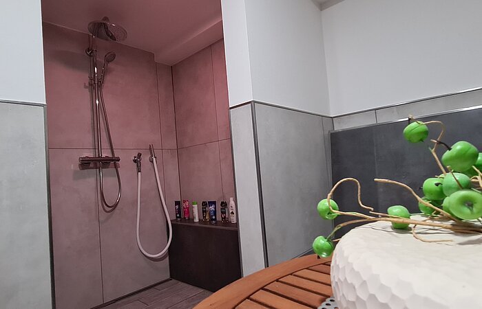 Welnessbereich Grau gefließte offene Dusche in einem grau gefließten Sanitärbereich.