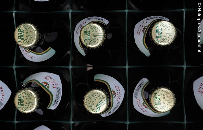 Kiste mit zwölf Felsenbräu-Bierflaschen, Draufsicht auf die Kronkorken.