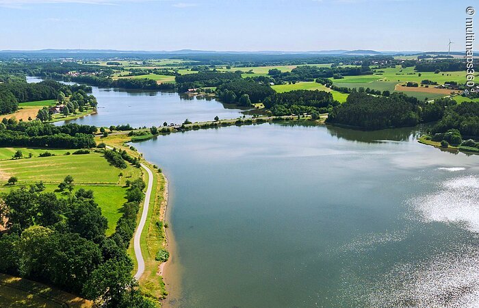 Luftbild von einem Teil des Rothsees. Der See ist umgeben von grünen Wiesen. Entlang des Ufers wachsen viele Bäume und Sträucher.