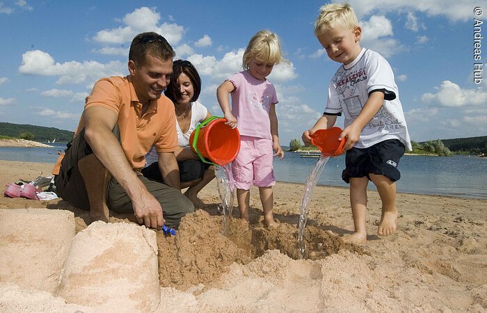 Badestrand Eine vierköpfige Familie spielt am Strand des Brombachsees in Ramsberg. Die zwei Kinder erfreuen sich am sandeln und genießen die Zeit.