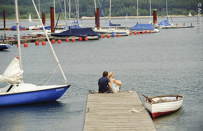 Segelhafen Auf dem Steg des Ramsbergers Segelhafens am Brombachsee genießen zwei Verliebte die wunderschöne Aussicht auf den Brombachsee und die Segelschiffe.