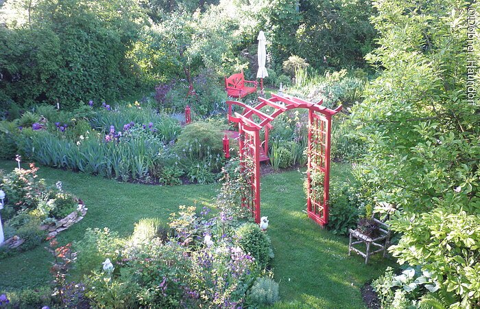 Rotes Holztor sticht im Garten heraus.