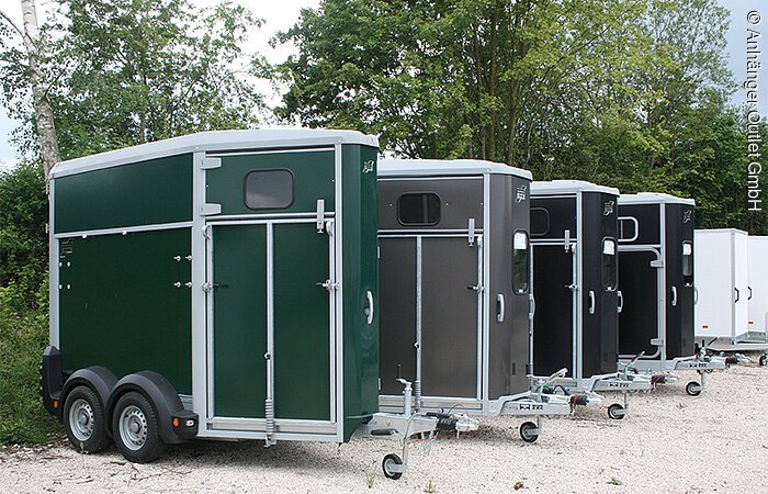 Movera Campingshop Gunzenhausen Grüne, grauer und zwei schwarze Anhänger stehen draußen.