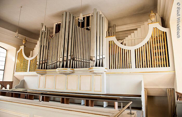 Eine große Orgel mit silbernen Orgelpfeifen und weißem Holz.