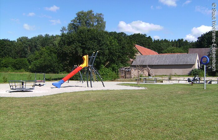 Spielplatz in Wolframs-Eschenbach - Reutern Bei sonnigem Wetter ist es hier auszuhalten. Rot-blau-gelbe Rutsche mit Rondell.