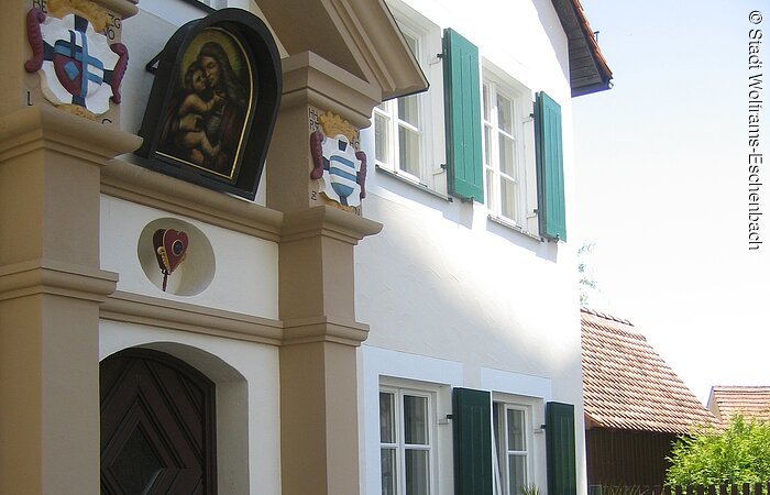 Das Pfarrhaus wurde 1975/76 in Anlehnung an seinen Vorgängerbau von 1667 neu errichtet. Teilweise original ist das frühbarocke Portal mit dem bunten Wappen der Deutschordensherren.