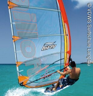 Ein Windsurfer lässt sich vom Wind über das türkis blaue Wasser leiten.