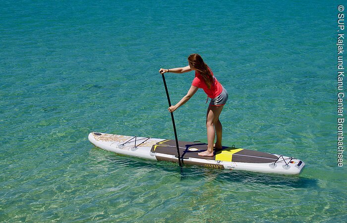 Eine junge Frau fährt mit ihrem Standuppaddle über das türkisblaue Wasser.