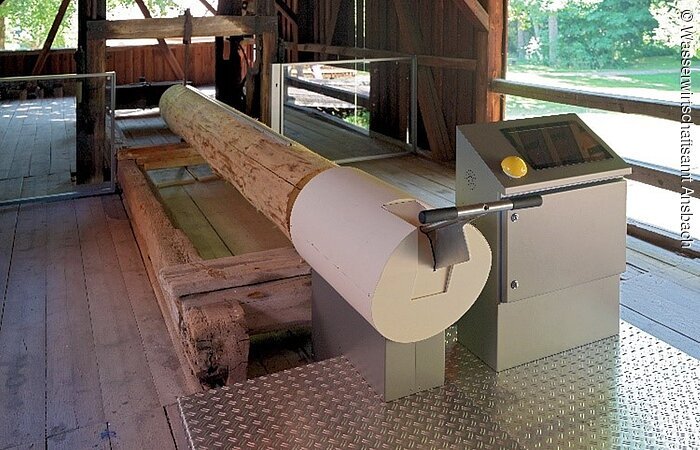 Sägespiel im ehemaligen Sägewerk der Mandlesmühle. Ein Baumstamm hängt in einer Sägemaschine.