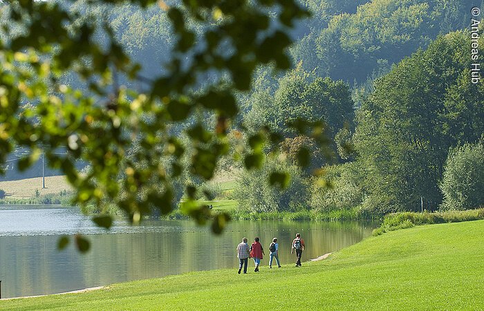 Wandern am Hahnenkammsee Vier Urlauber wandern direkt am Ufer des Hahnenkammsees bei Hechlingen am günen Ufer entlang.