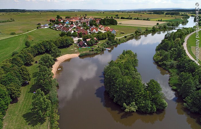 Zuleiter Ornbau Ein Luftbild des Zuleiters in Ornbau. Am Ufer wachsen grüne Bäume auf grünen Wiesen. Im hinteren Bildabschnitt sieht man die Häuser eines kleinen Dorfes.