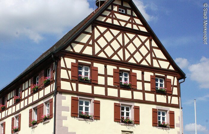Ansicht auf das Merkendorfer Rathaus, auf dem sich ein Storchennest befindet.