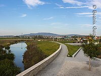 Uferweg Fußgängerweg am Randes eines Bachs. Am Ufer grüne Wiesen.
