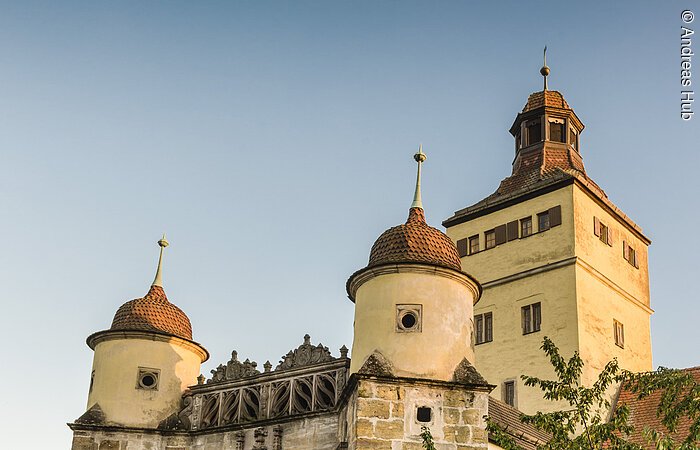 Eine Brücke aus Stein führt in erin Steintor mit zwei runden Türmchen. Dahinter ein großer rechteckiger Turm.
