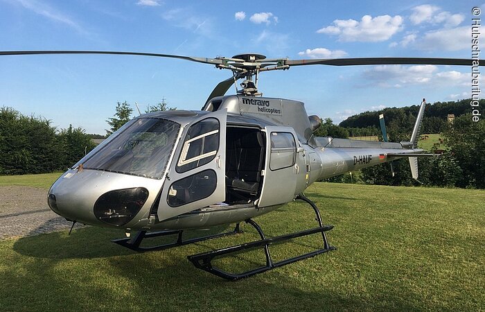 Grauer Hubschrauber mit offener Türe.