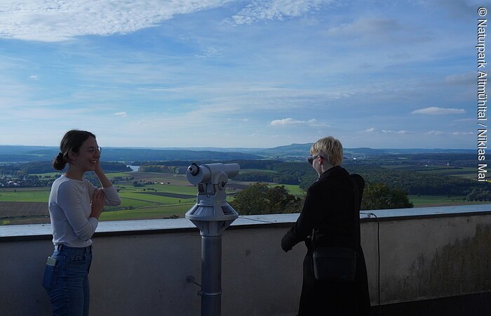 Heidenheim Burg Hohentruedingen Ausssichtspunkt Zwei Personen stehen an einer Aussichtsplattform mit Fernrohr und Blick auf eine weite Landschaft mit Feldern und Wald.